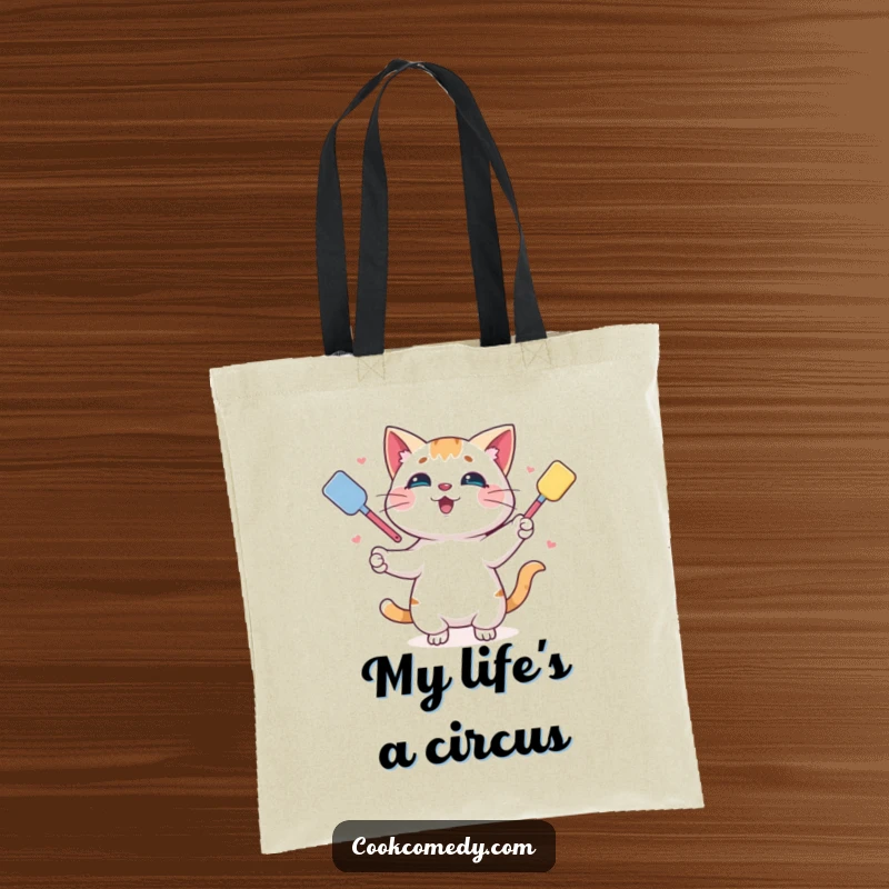 Funny tote bag with a playful cat juggling colorful spatulas, ideal for carrying essentials with a splash of personality.